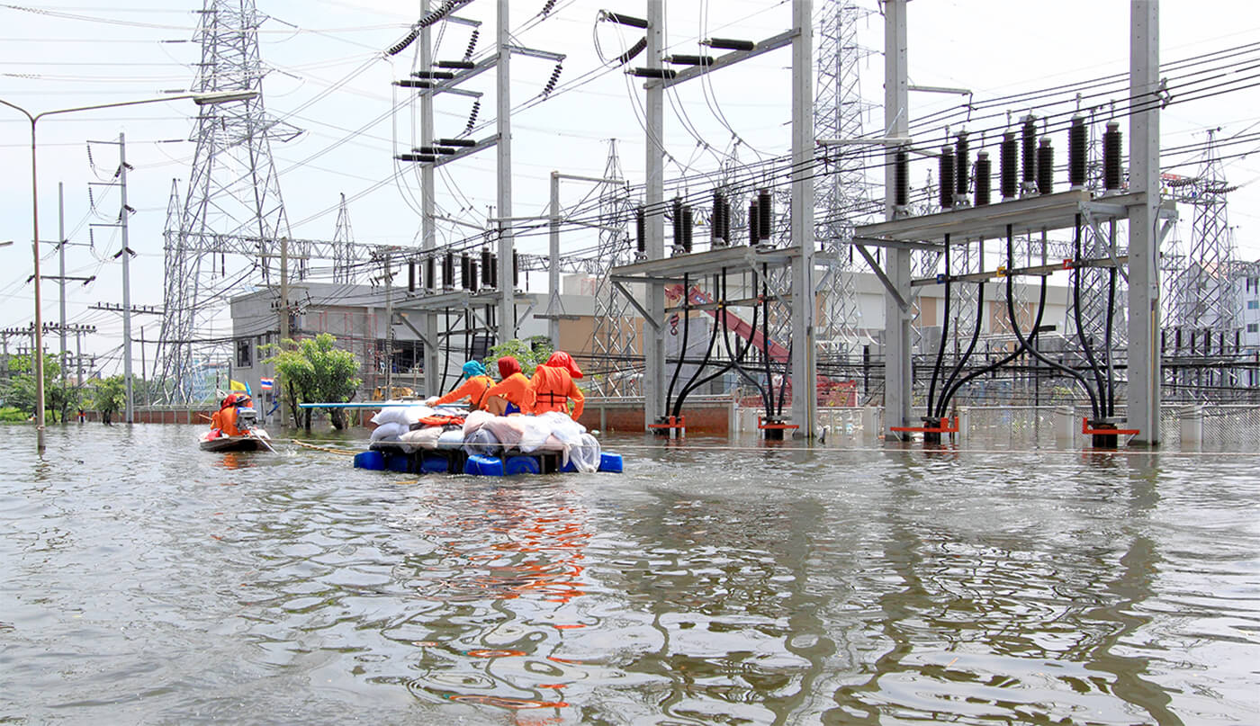 Workers in rafts float by a flooded substation