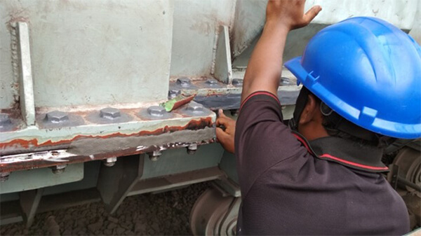 Un hombre con un casco azul trabaja para sellar una fuga en un transformador