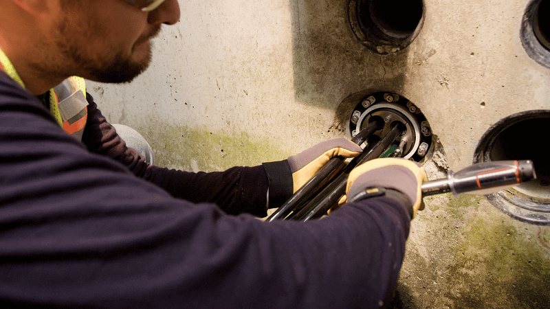Ein Arbeiter dichtet ein Rohr in einem Elektrogewölbe ab