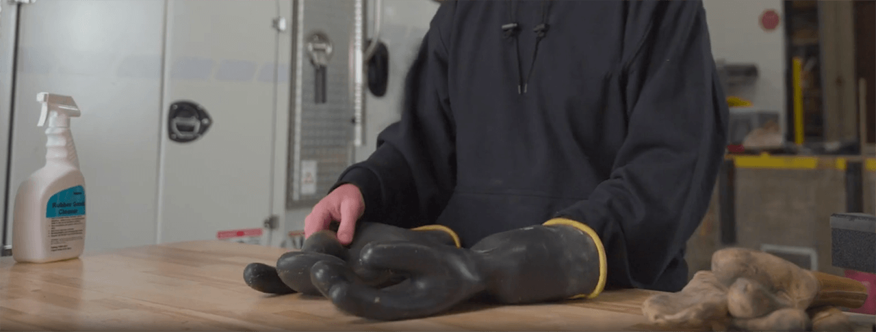 Un monteur de lignes examine les gants en caoutchouc de son EPI