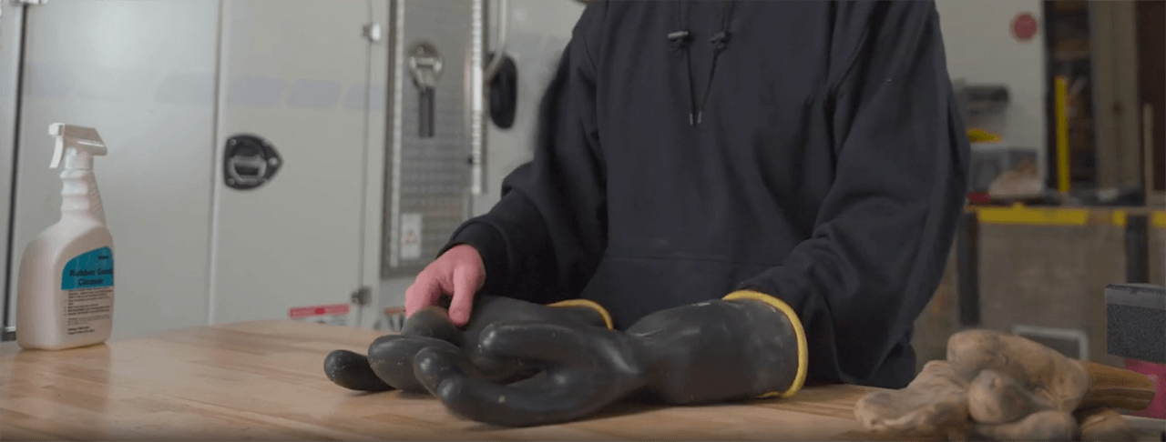 Un liniero examina sus guantes de caucho para EPP