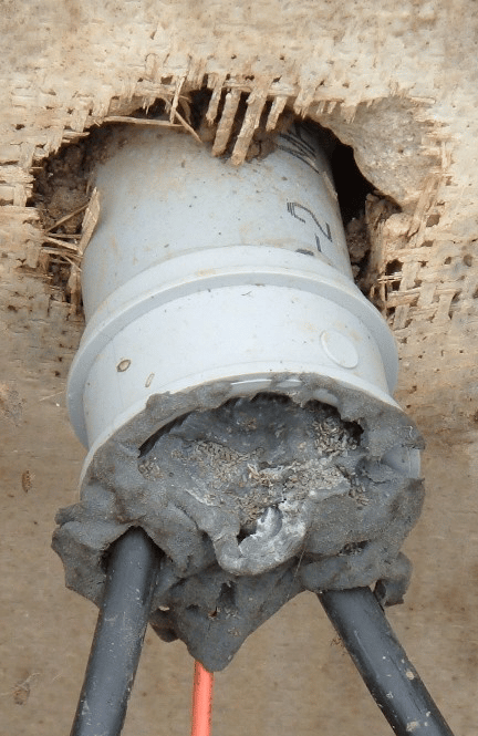 Sagging duct putty attempting to seal a conduit with electrical wires coming out.