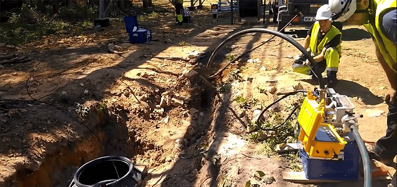 Zwei Arbeiter überwachen eine Kabel-Jetting-Maschine bei der Installation von Kommunikationskabeln