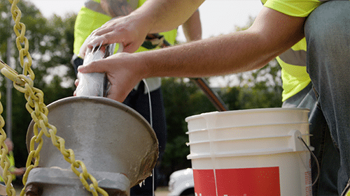 Aplicación a mano del lubricante Polywater J en un cable eléctrico a medida que lo introducen en un ducto