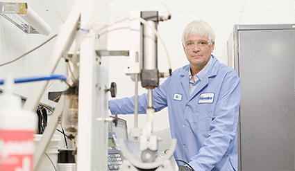 a Polywater R&D scientist examines a lubricated section of electrical cable on Polywater's friction testing table.