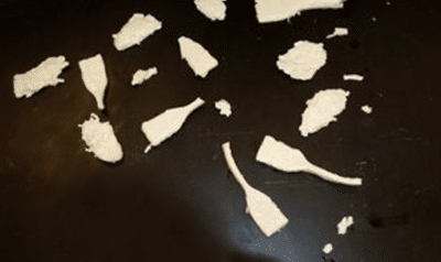 The shards of a shattered plastic conduit strewn about a black countertop.