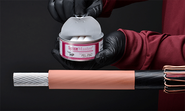 Two hands hold open a small tin with three white, electrical-cable cleaning towelettes inside. The label on the can reads "SpliceMaster Type HP". A stripped electrical cable is in the foreground ready for cleaning before splicing.