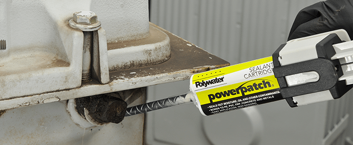 A hand squeezes a dispensing gun with a Polywater PowerPatch cartridge onto a leaking bolt of an electrical transformer.