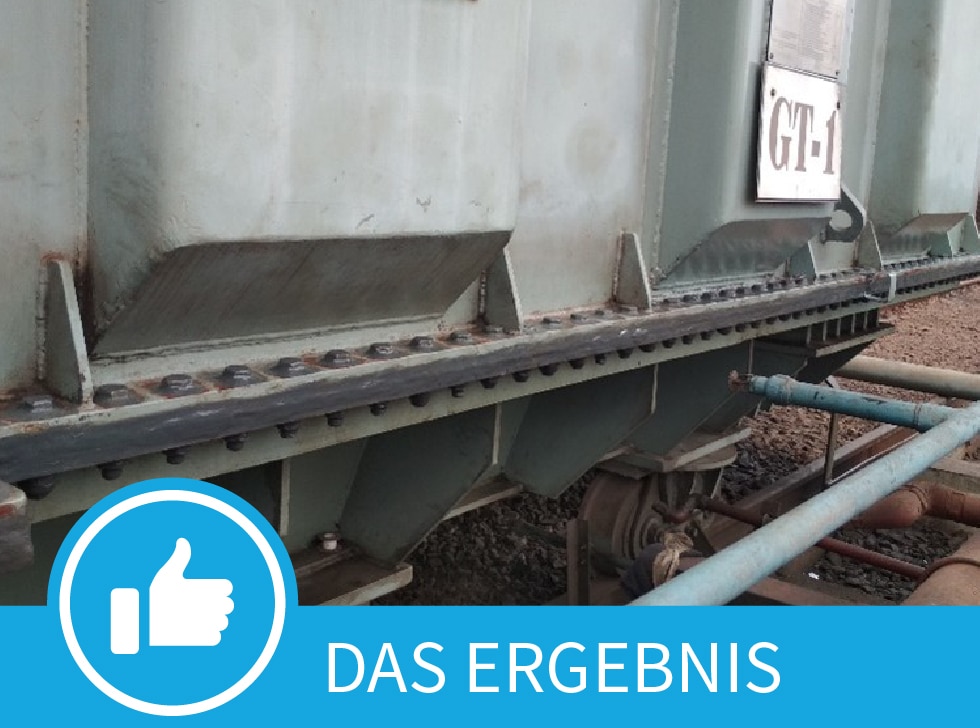 Ein alter, grauer, elektrischer Transformator, der Anzeichen von Alterung und Rost aufweist, mit einem blauen Banner am unteren Bildrand mit der Aufschrift „Das Ergebnis“.