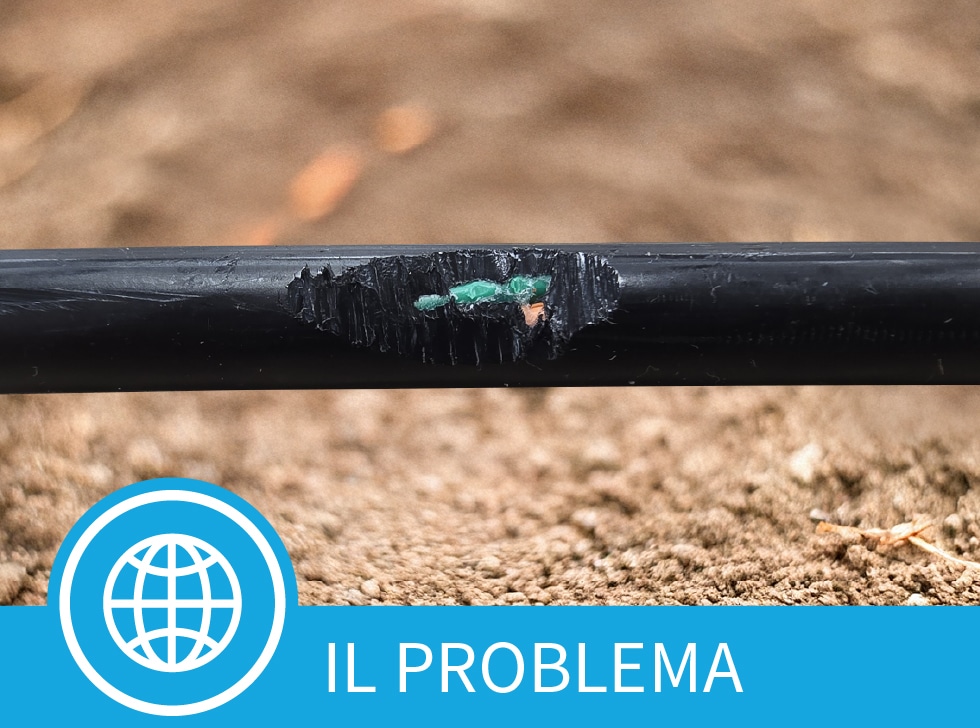 Un rivestimento del cavo in fibra danneggiato che mostra cavi in fibra ottica esposti su uno sfondo di terra. Nella parte inferiore dell'immagine compaiono le parole 