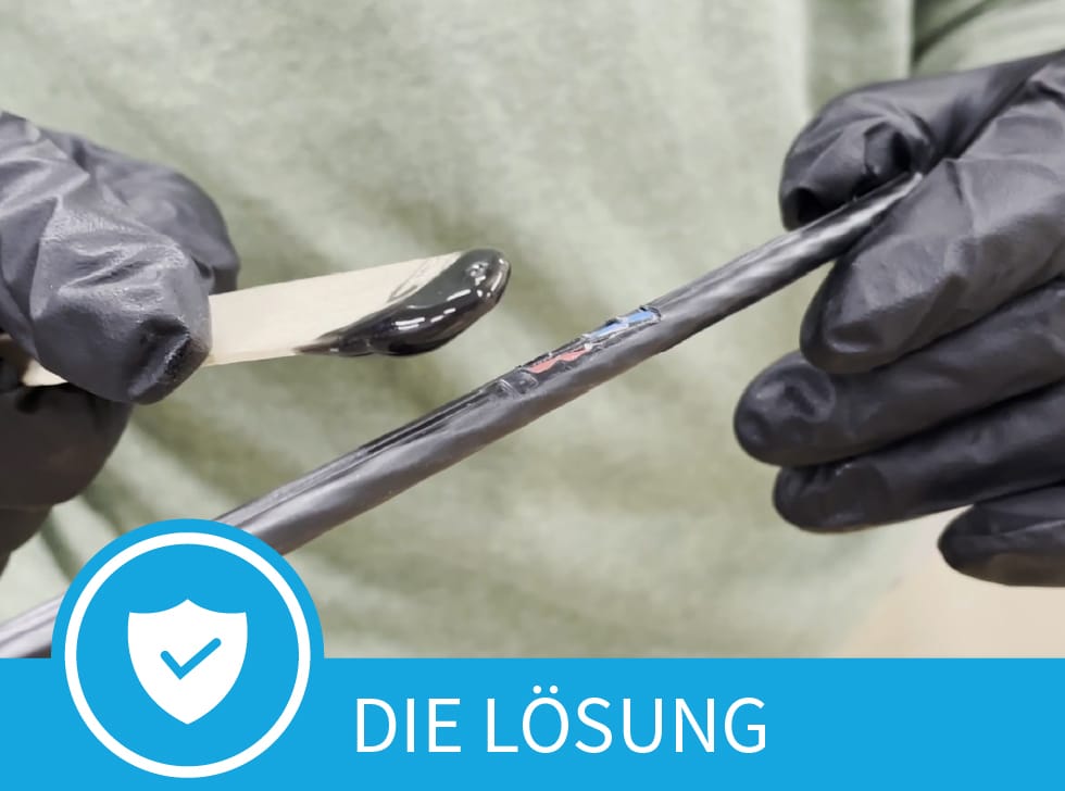 Ein schwarzes Paste-Polywater CJR Kabelmantel-Reparatur- auf dem Ende eines Eisstiels wird auf die beschädigte Stelle eines Glasfaserkabelmantels aufgetragen. Am unteren Rand des Bildes stehen die Worte „Die Lösung“.