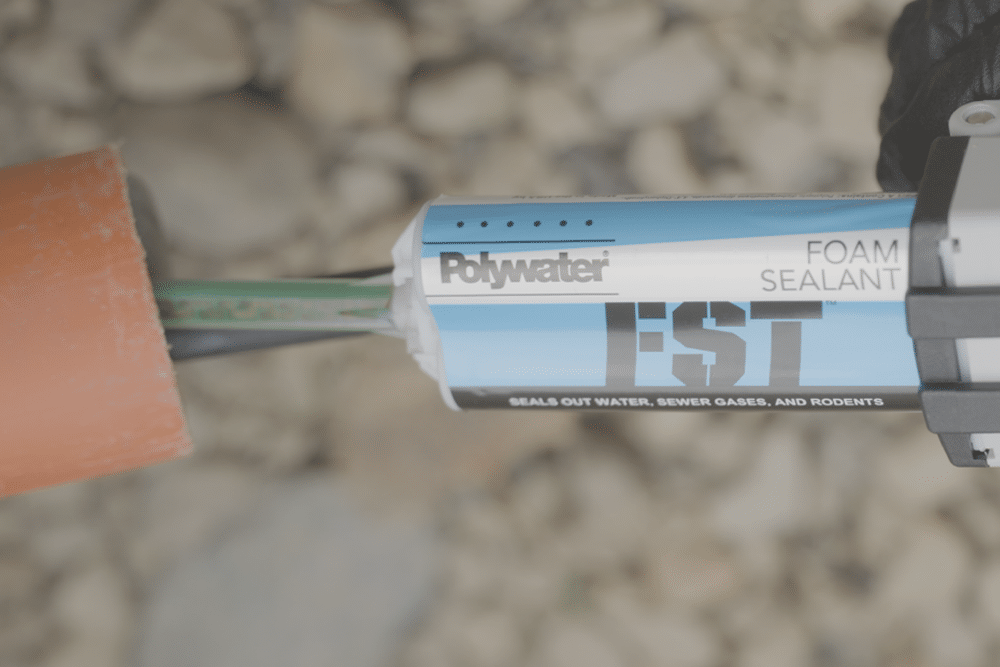 Polywater FST-MINI being dispensed into an orange communication duct with a coax cable coming out of it.